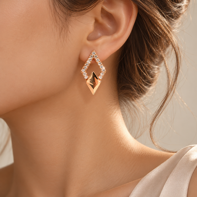 Close-up of rose gold-tone earrings featuring sparkling stones and geometric detailing.