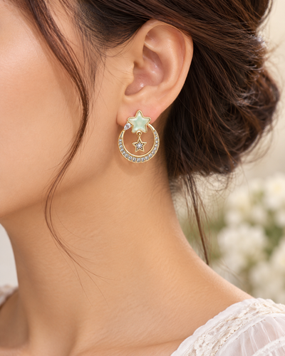 Model wearing elegant gold star drop earrings with mint-green accents and crystal detailing.