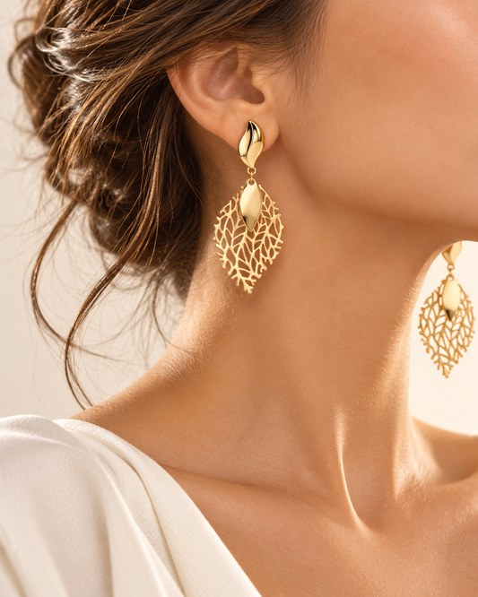Model wearing elegant gold-tone leaf statement earrings with delicate nature-inspired filigree.