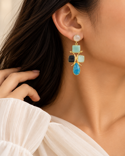 Close-up of multicolour statement earrings featuring round, square and teardrop gemstone-inspired settings.