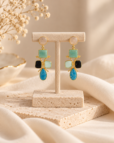 ANOVRA multicolour stone drop earrings styled with minimal luxury props against a soft cream background.