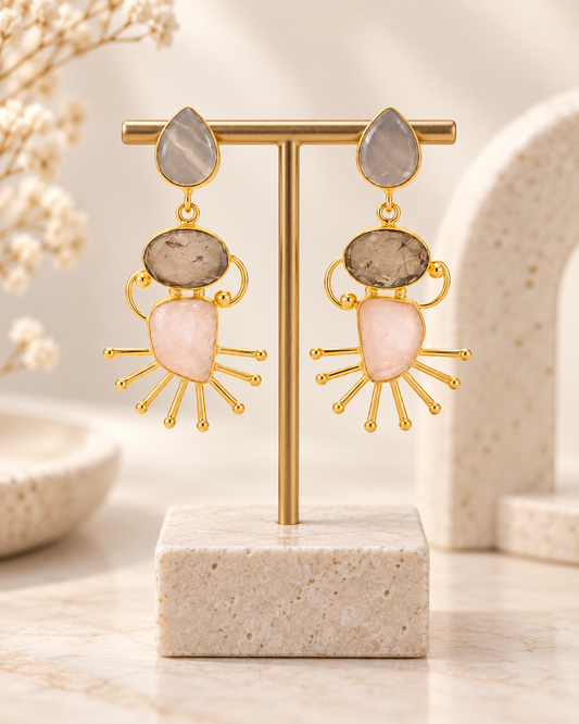 ANOVRA multicolour gemstone-style statement earrings displayed with minimal luxury props on a cream background.