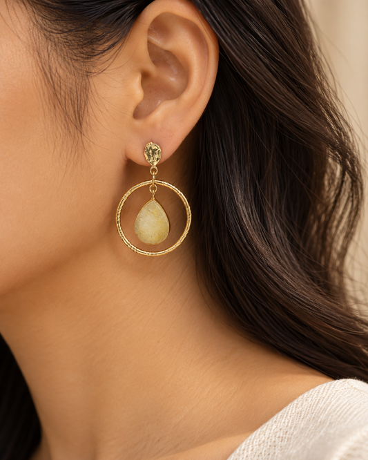 Model wearing elegant gold-tone hoop drop earrings with golden-yellow teardrop pendants.