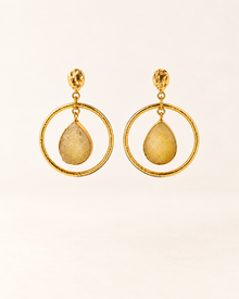 ANOVRA gold teardrop hoop earrings featuring textured circular frames and golden-yellow dangling stone accents.