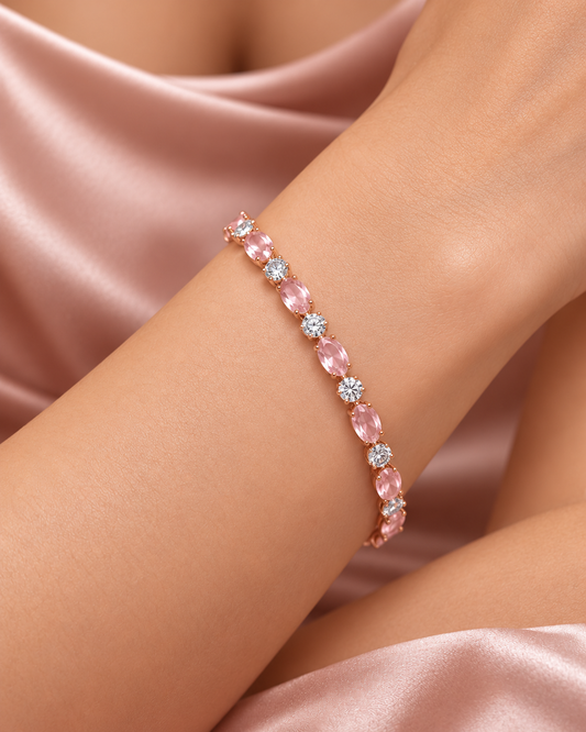 Close-up of a rose gold tone bracelet with oval blush pink stones and round clear accents styled on a model's wrist.
