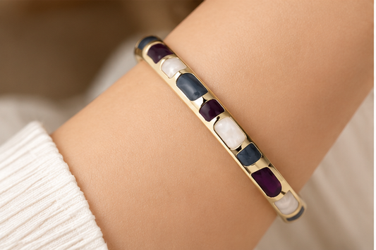 Close-up of Anovra multicolor enamel gold-tone bangle bracelet worn on model wrist